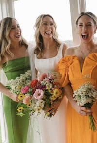 three bridesmaids laughing while holding bouquets